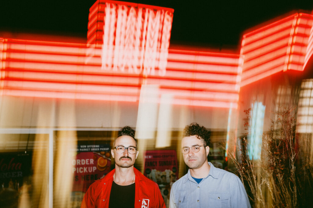 Hello Yes photographed in front of bright neon red lights 