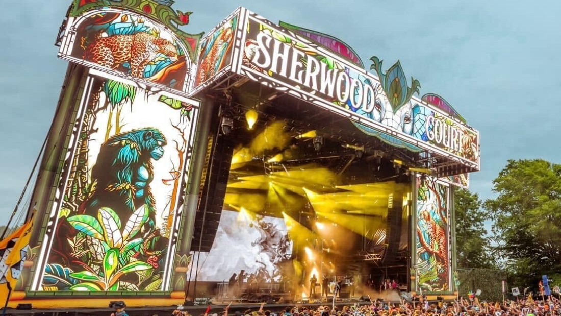 Photo of a colorful stage and full crowd in front of it at Electric Forest