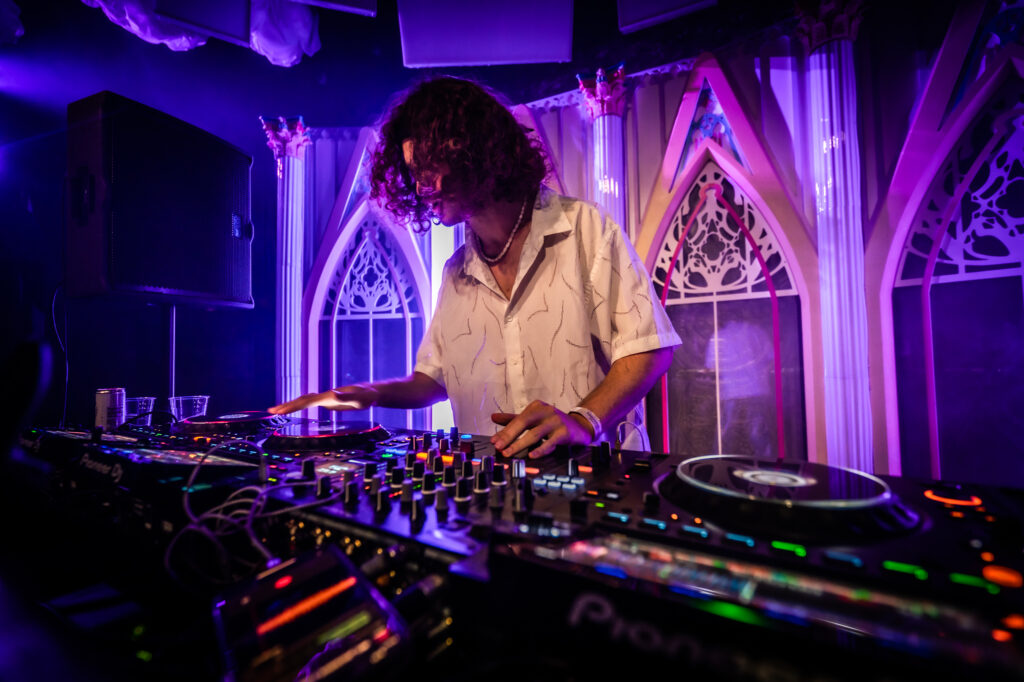 Photo of a DJ in a white shirt performing
