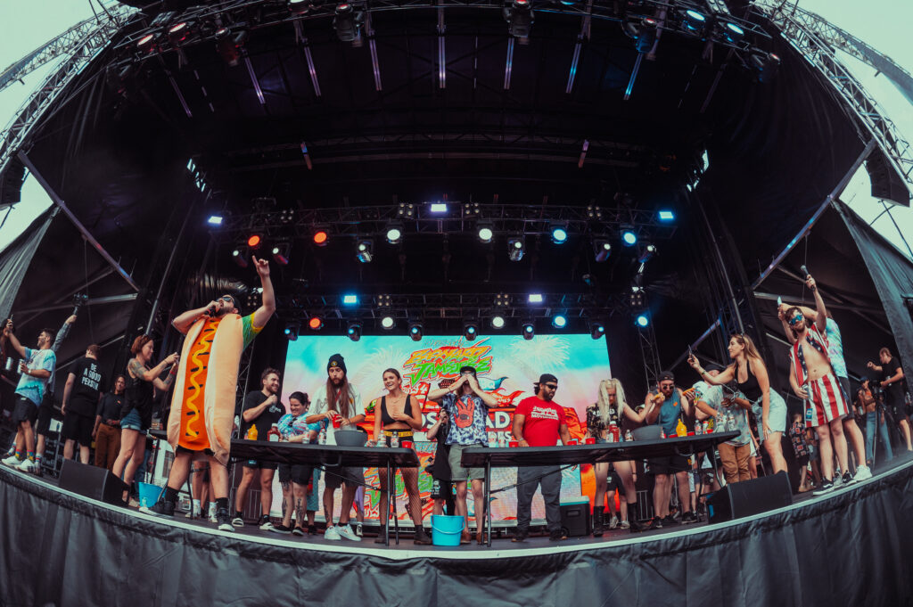 group of people on stage doing a hot dog eating contest