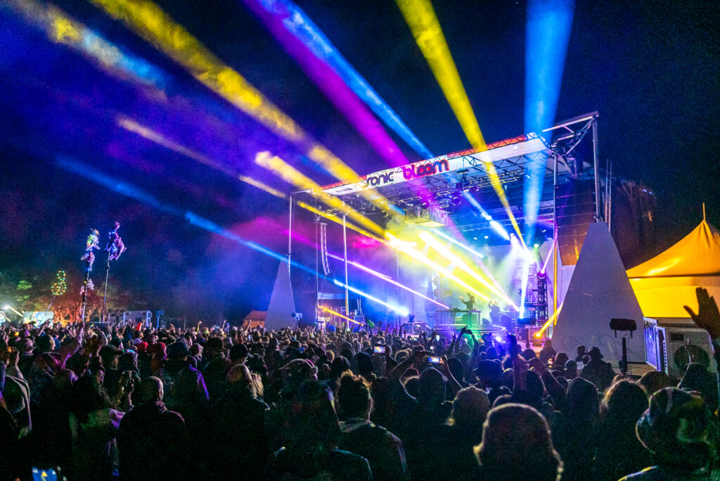 Lights shooting out from a stage over a festival crowd