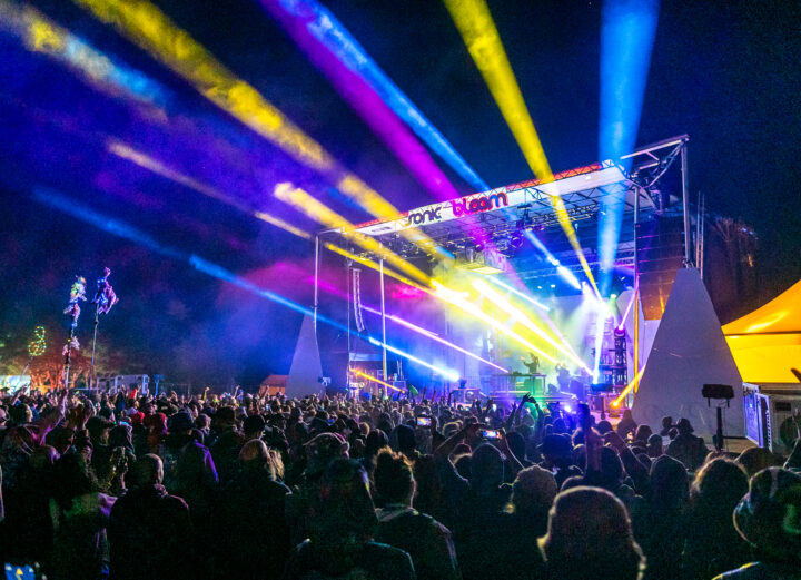 Lights shooting out from a stage over a festival crowd