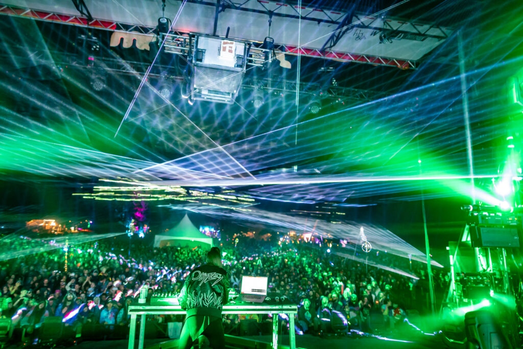 Lights shooting out from a stage over a festival crowd