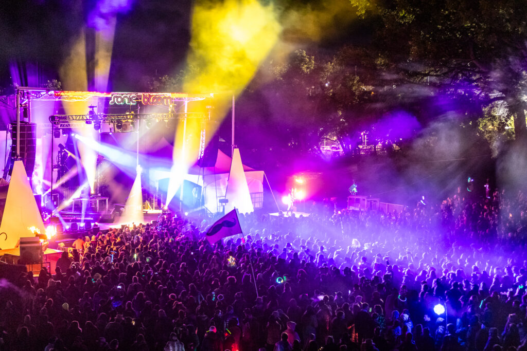 Lights shooting out from a stage over a festival crowd