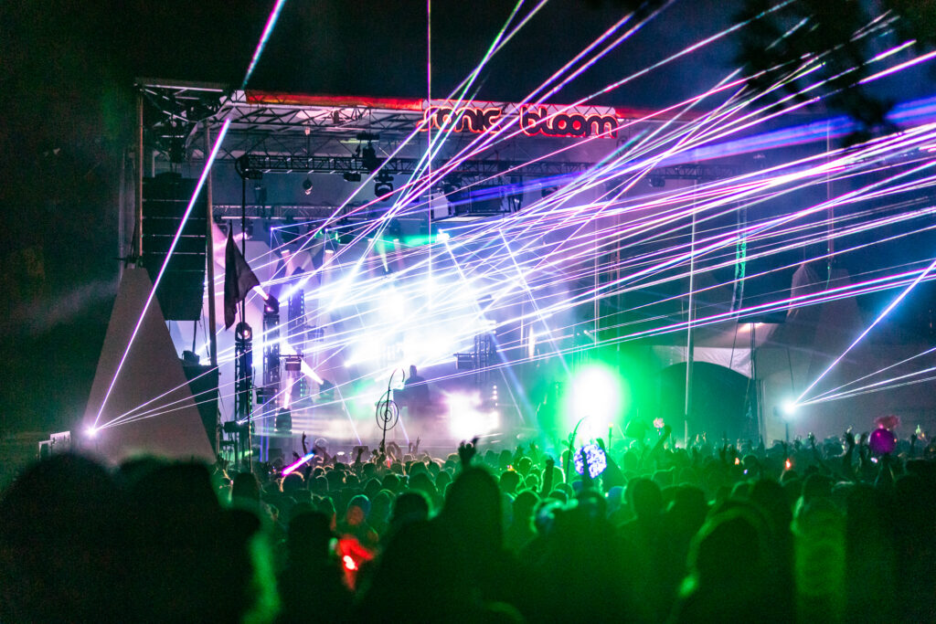 Lights shooting out from a stage over a festival crowd