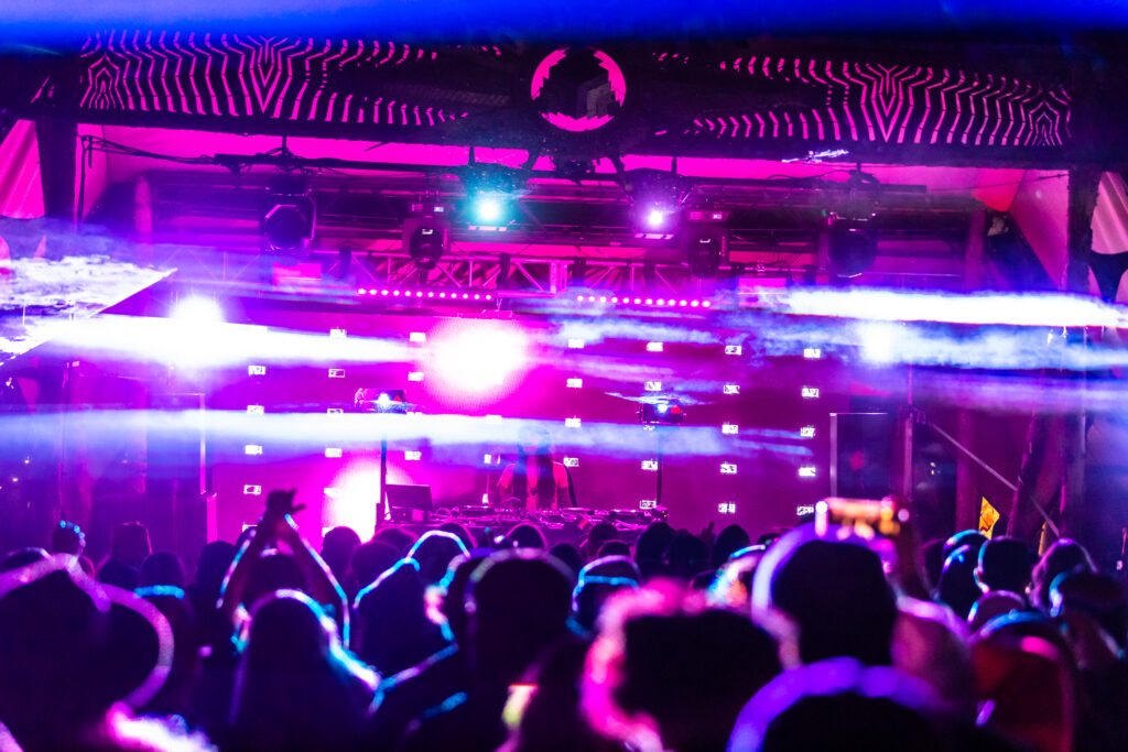 Lights shooting out from a stage over a festival crowd