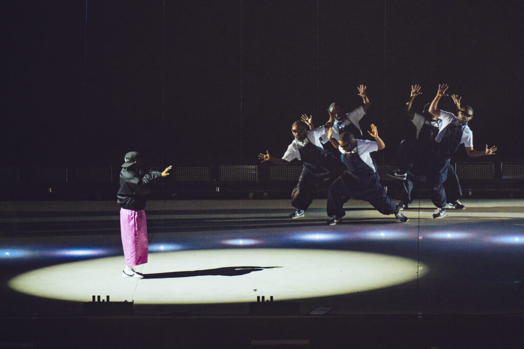 Photo of Kendrick Lamar in pink pants looking at dancers