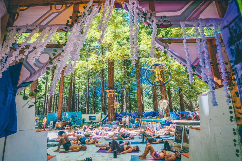 Photo of people doing yoga among red wood trees.