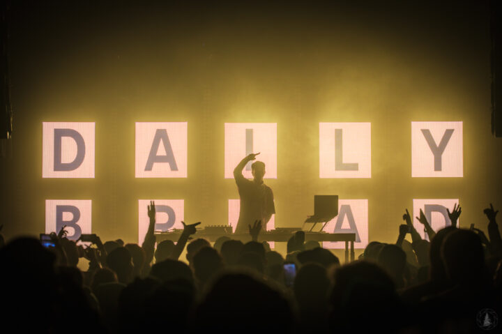 Photo of a DJ raising his hand before a crowd