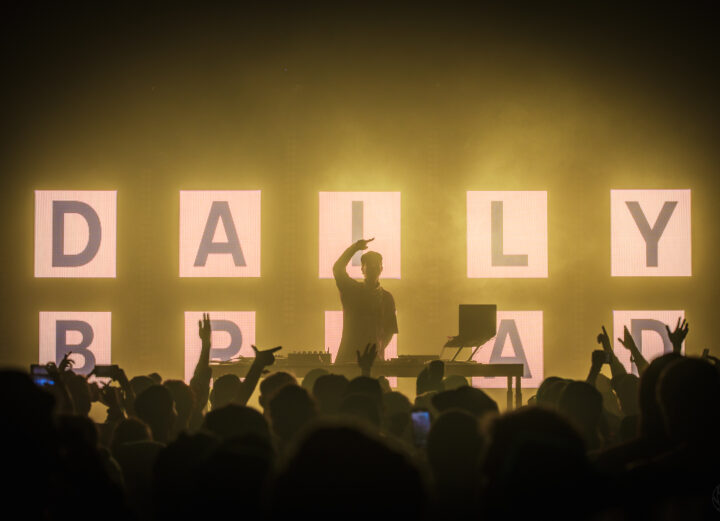 Photo of a DJ raising his hand before a crowd