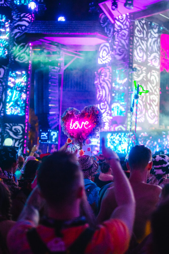 someone holding a 'Love' totem in a crowd with stage in the background