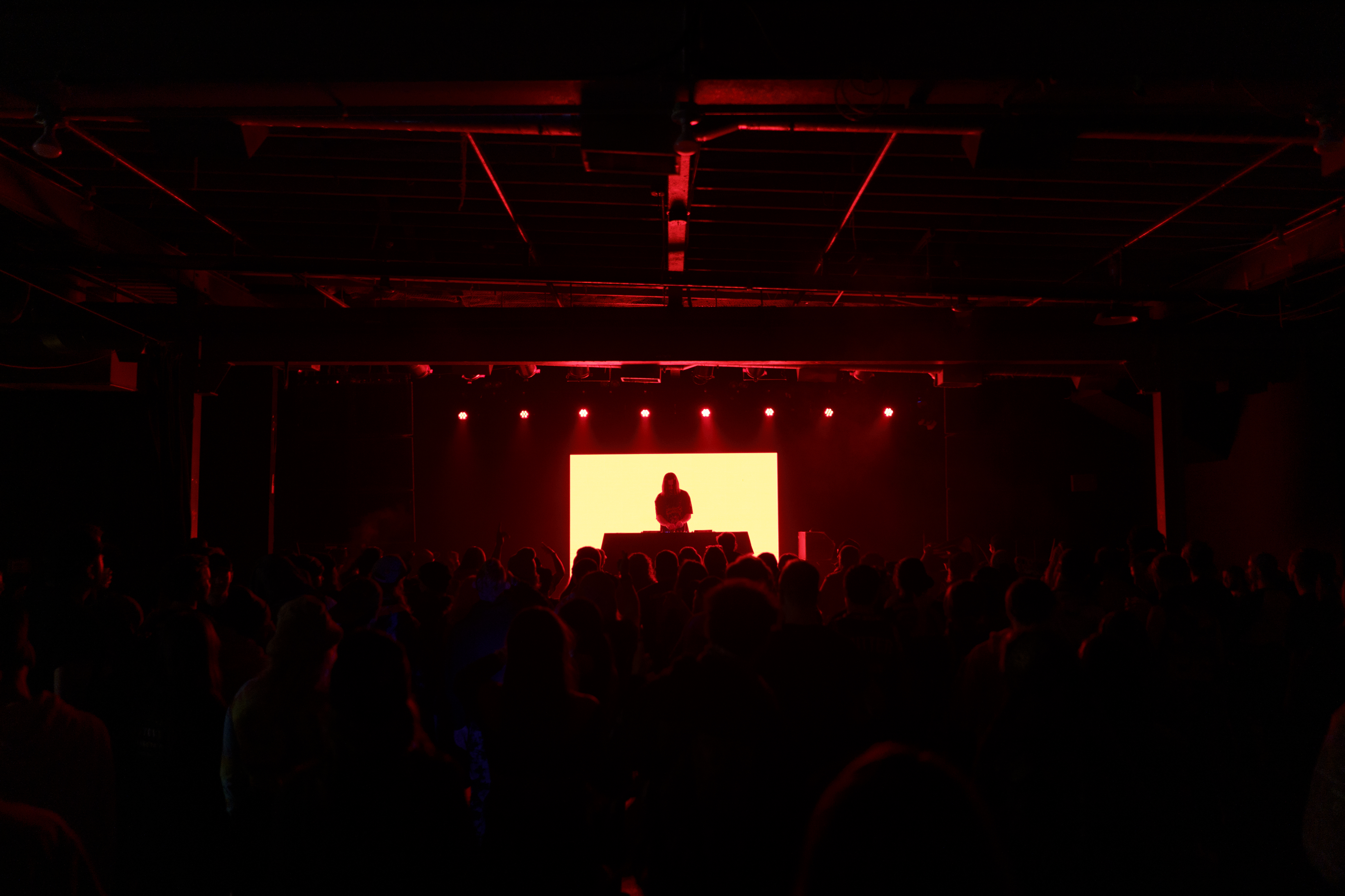 Meduso performing in front of red backdrop and LED screen in dark room