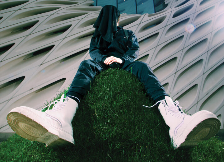 Modapit press photo: sitting on grass hill with face covered.