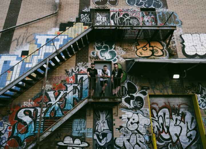 Ternion Sound trio standing outside on staircase covered in graffiti