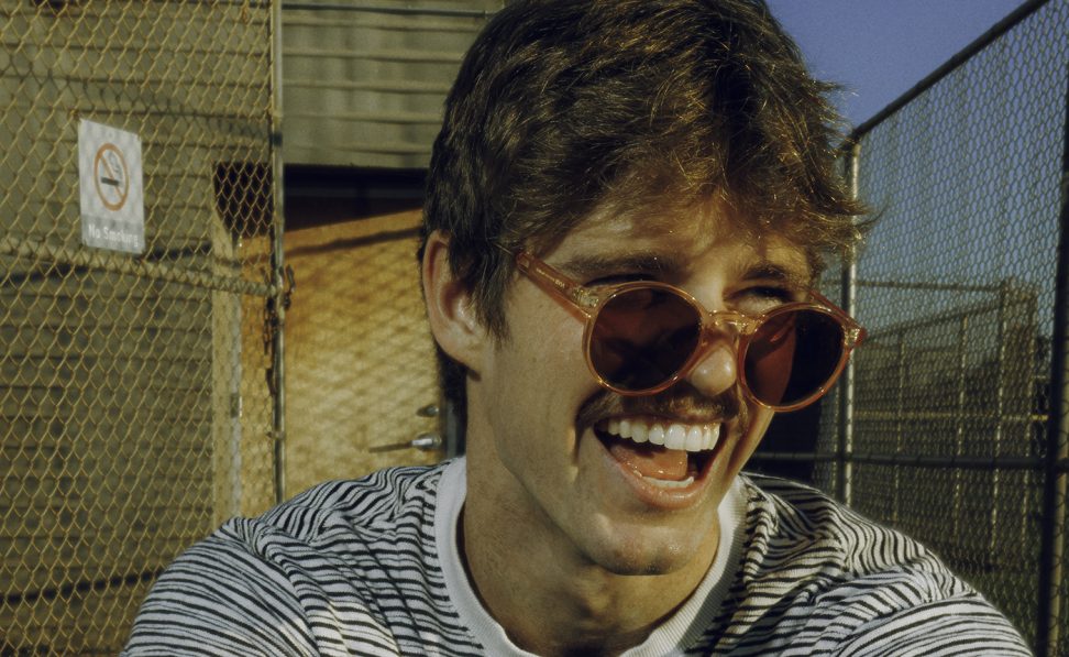 It's Murph — man smiling with glasses on, outside, wearing a black and white stripped shirt