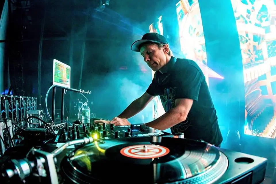 DJ Tipper playing a set on stage in front of a blue LED wall