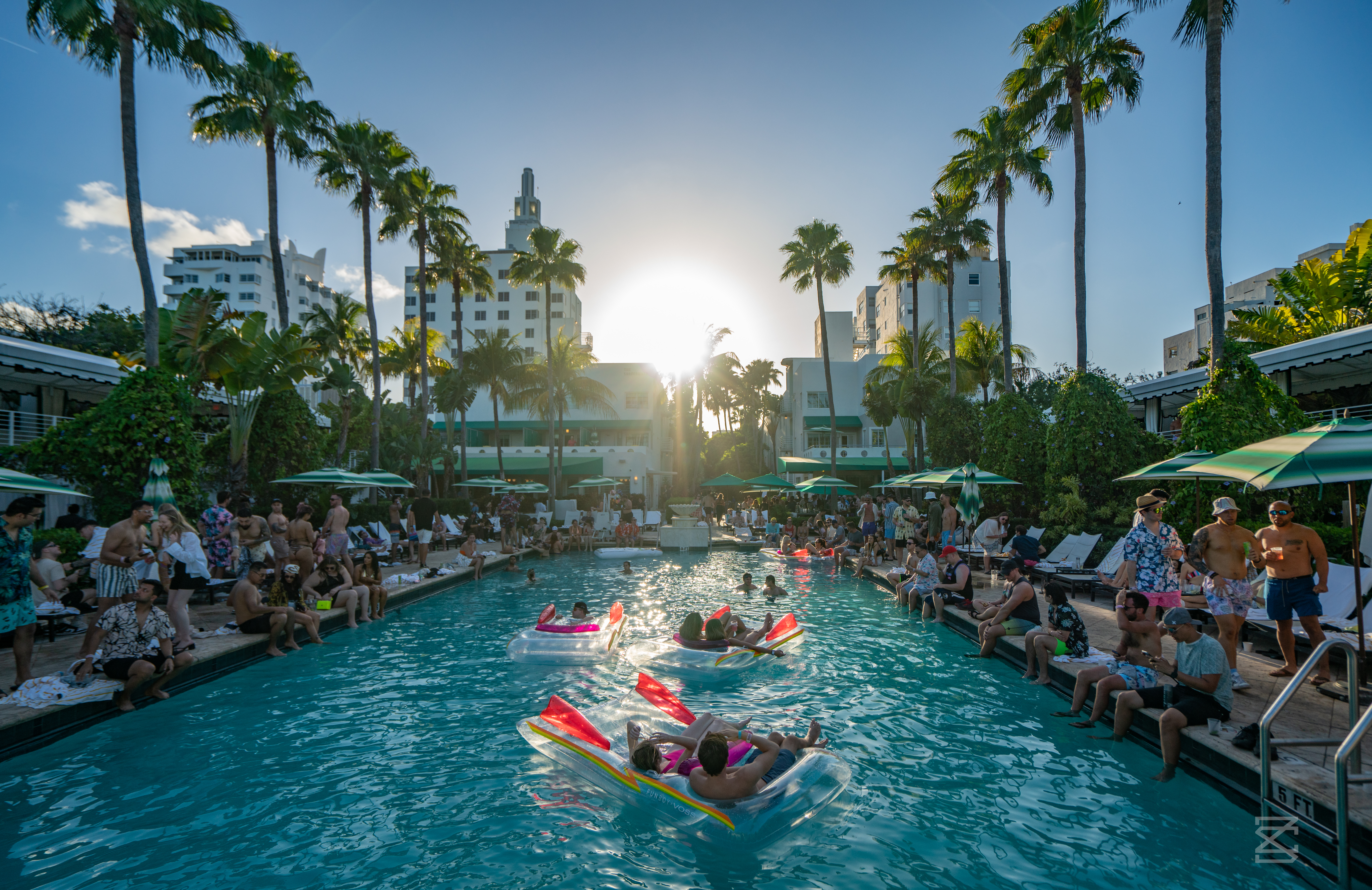 Surfcomber hotel pool in Miami beach — people swimming as the sun sets over Miami.