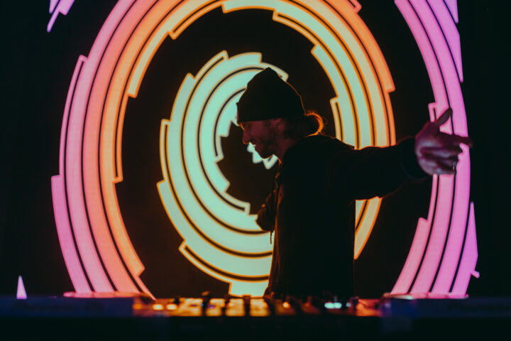 Super Future DJ dancing on stage in front of LED screen.