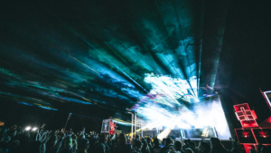 lasers cutting through fog in front of stage at music festival sacred acre festival in alaska