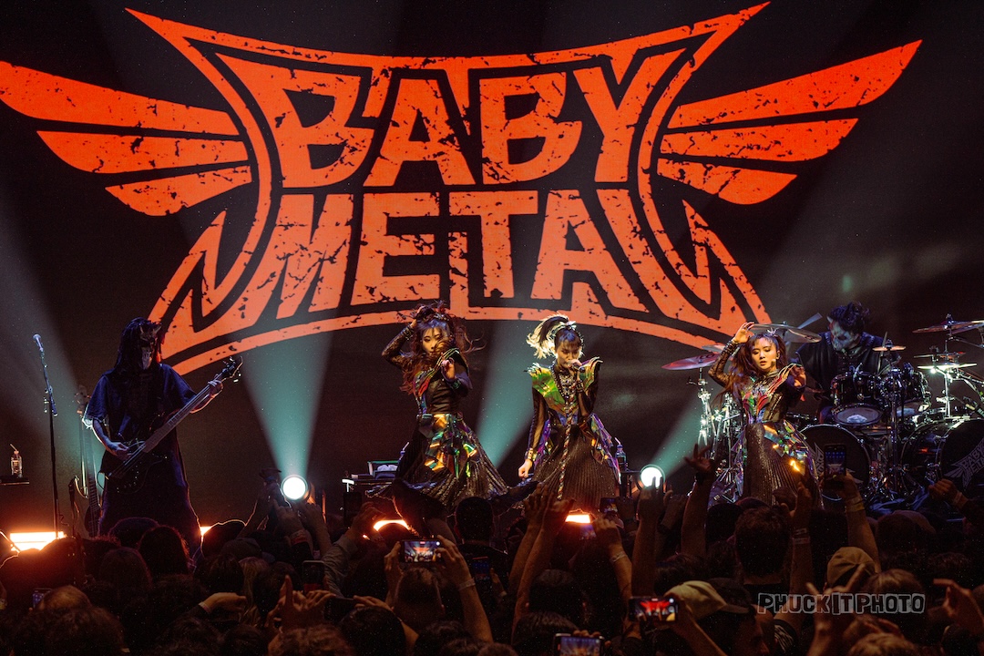 BABYMETAL plays music to large crowd with their logo behind them