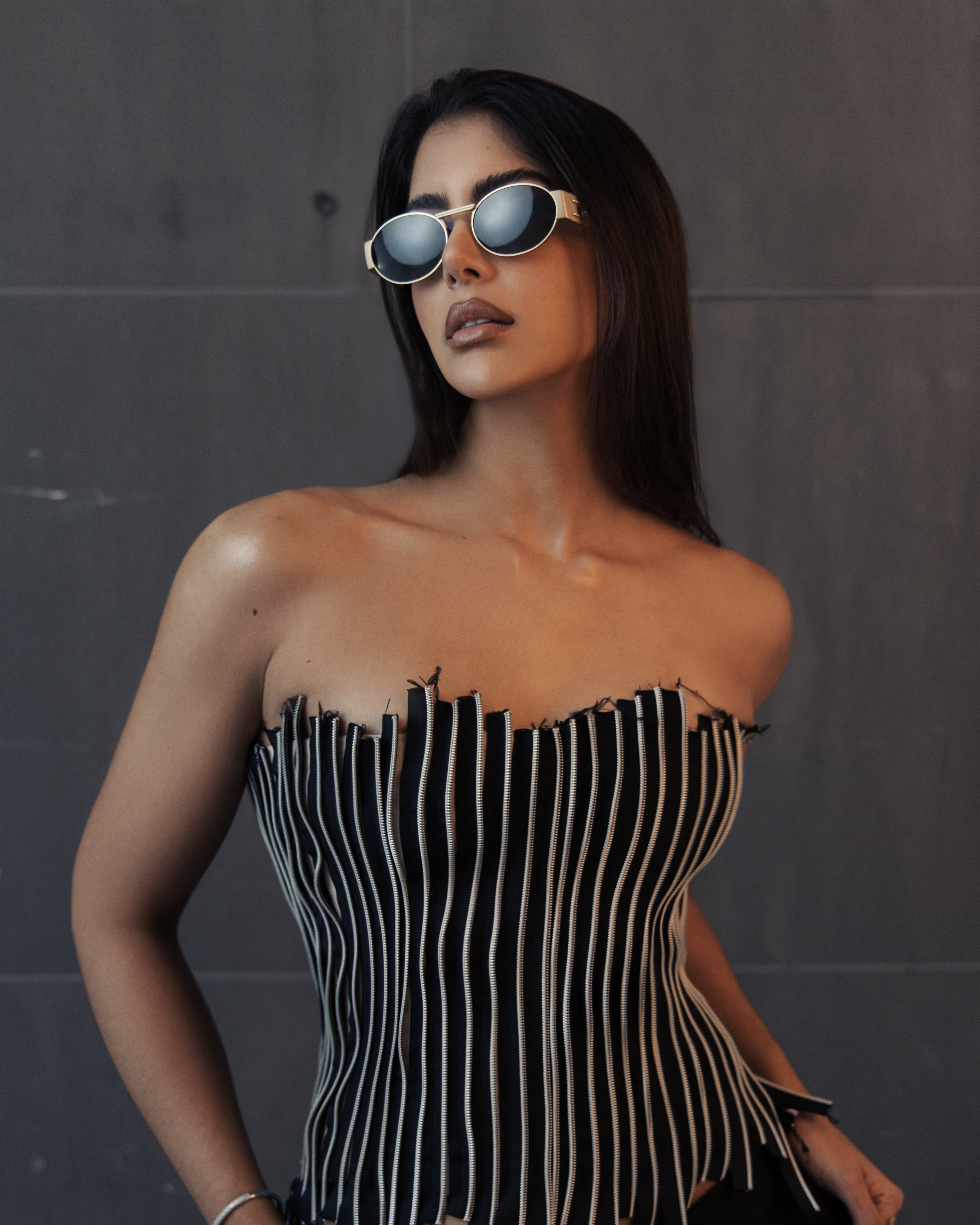 Amal Nemer posing in front of grey background, wearing sunglasses