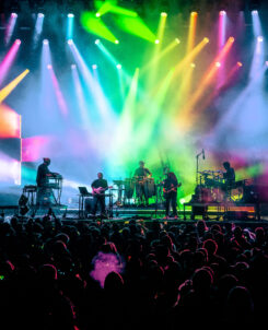 Bright colorful lights on a massive stage while jam band plays to large crowd